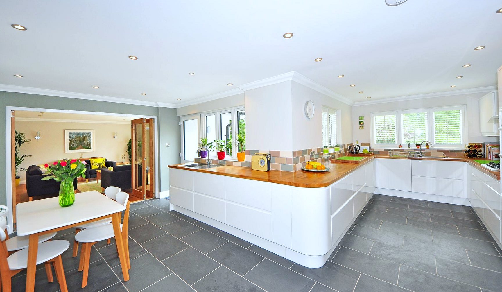Newly fitted white kitchen with timber worktops, a tiled splashback and slate floor tiles