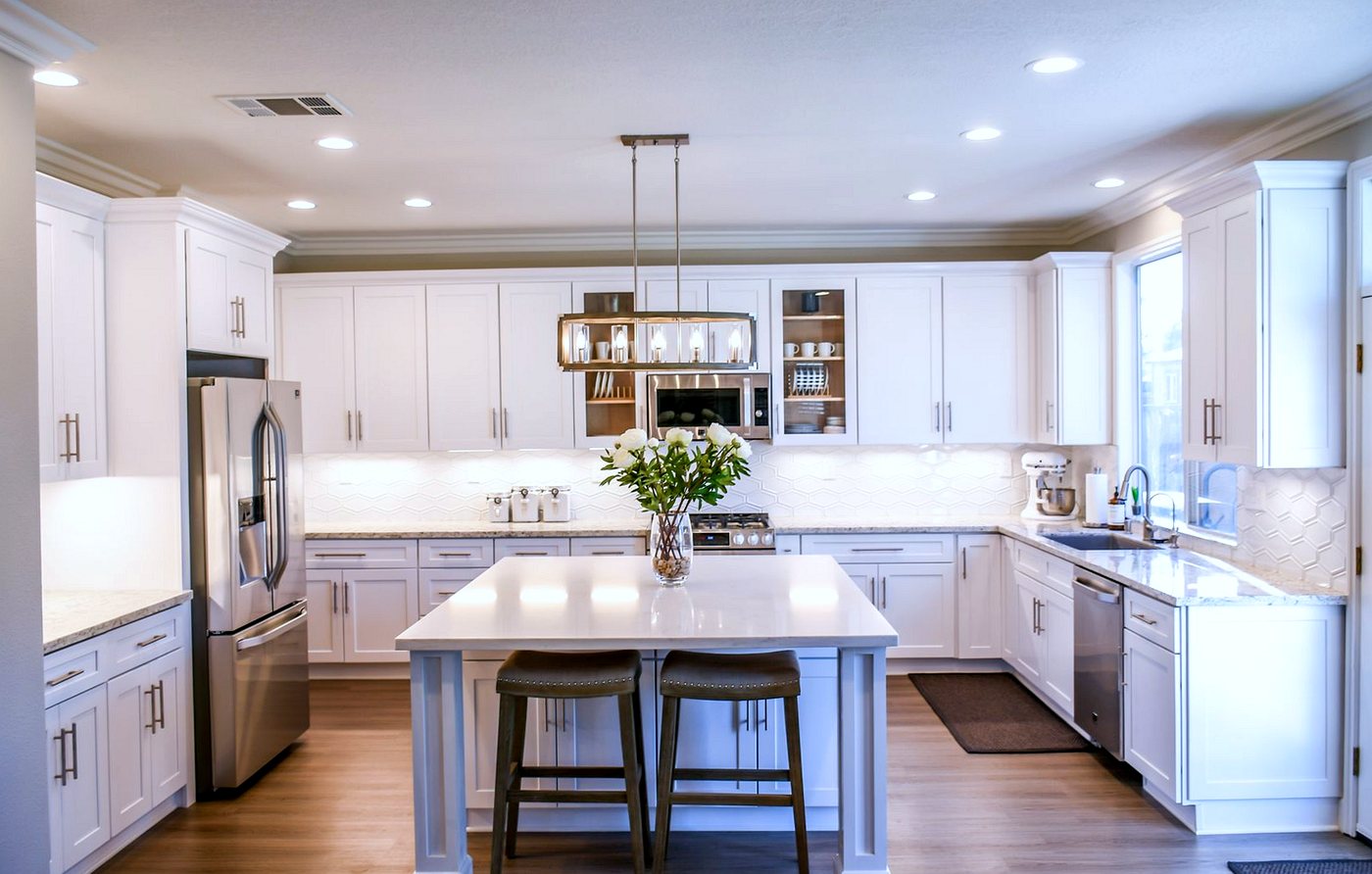 White fitted kitchen with island, stone worktops and a tiled splashback